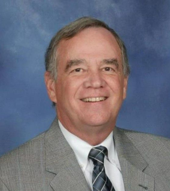 A man in a suit and tie is smiling for the camera