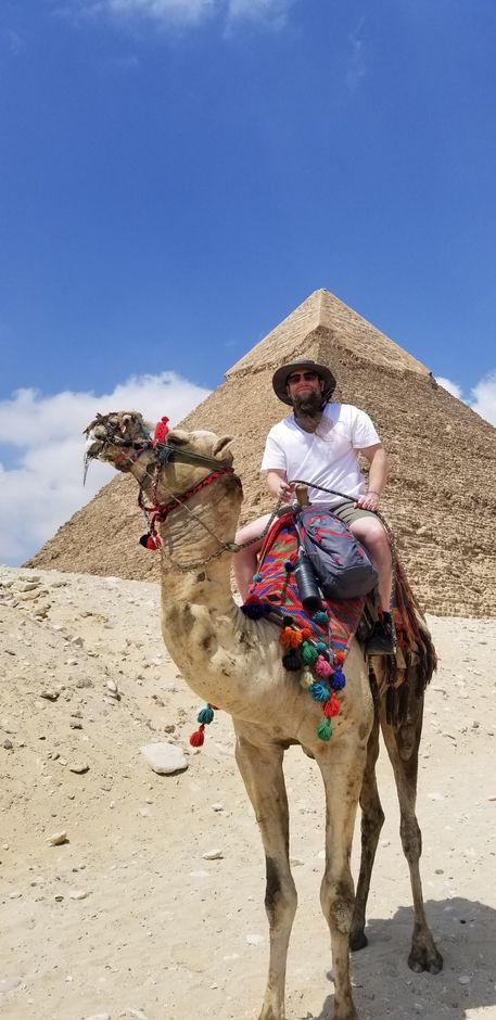 hypnotist Levi Gann on a camel in front of the pyraminds in Egypt