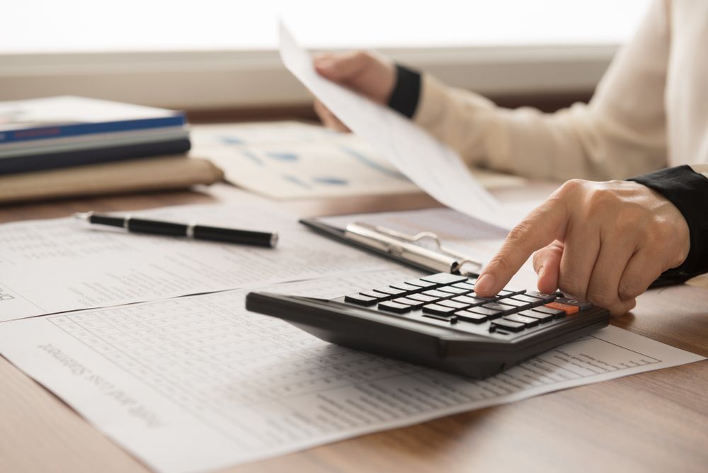 Person Using a Calculator With Paperwork on a Desk — Precision Financial & Tax In Ross Creek, VIC