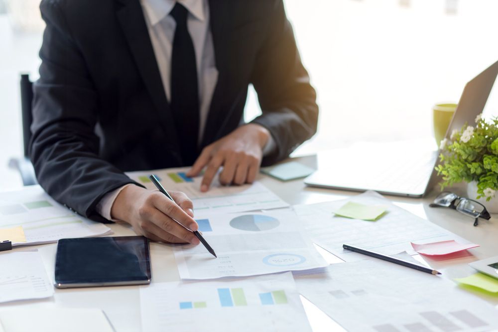 Person in Suit Points at Charts and Graphs on a Desk With a Laptop — Precision Financial & Tax In Ross Creek, VIC