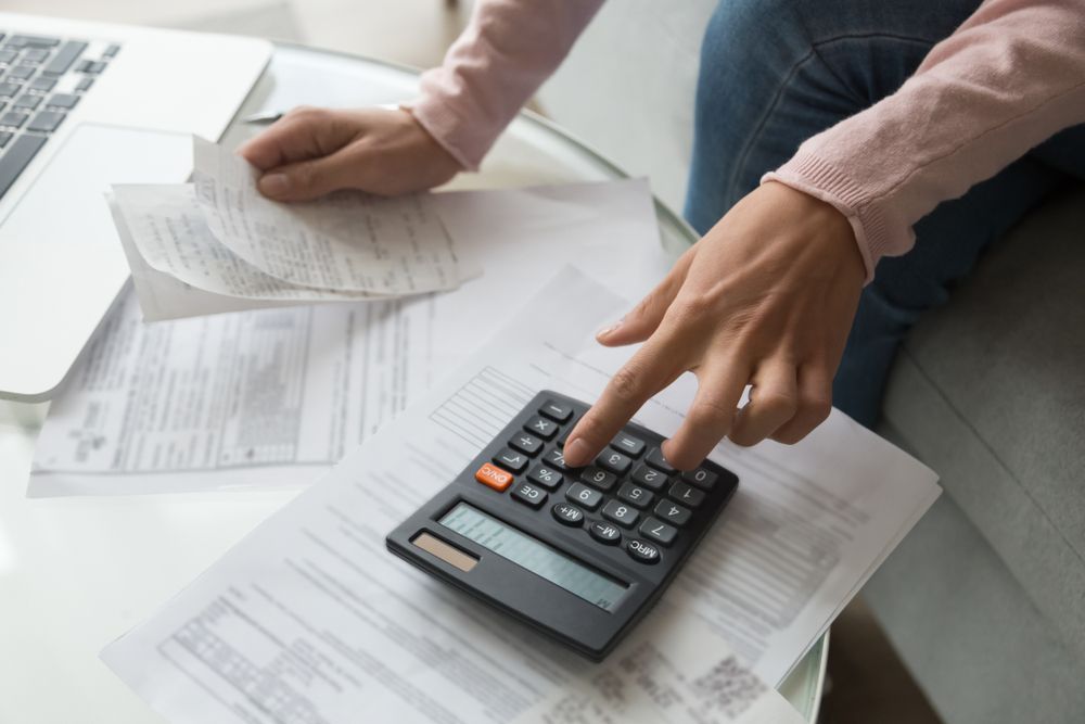 Person Using a Calculator While Reviewing Bills — Precision Financial & Tax In Ross Creek, VIC