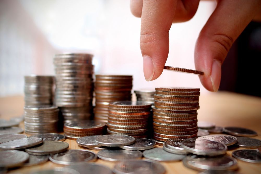 Hand Adding a Coin to a Stack of Coins — Precision Financial & Tax In Ross Creek, VIC
