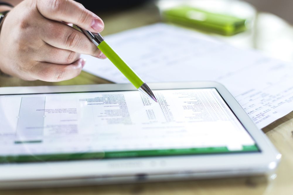 Hand Holding a Green Pen Points to a Tablet Screen Displaying Data — Precision Financial & Tax In Ross Creek, VIC