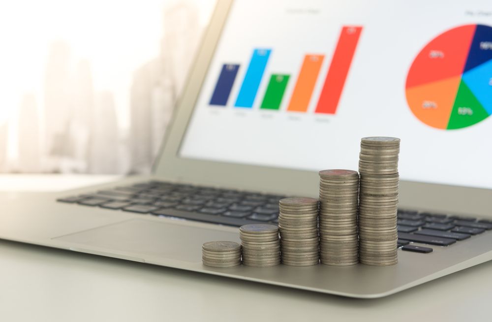 Laptop Displaying Colourful Charts With Stacks of Coins — Precision Financial & Tax In Ross Creek, VIC