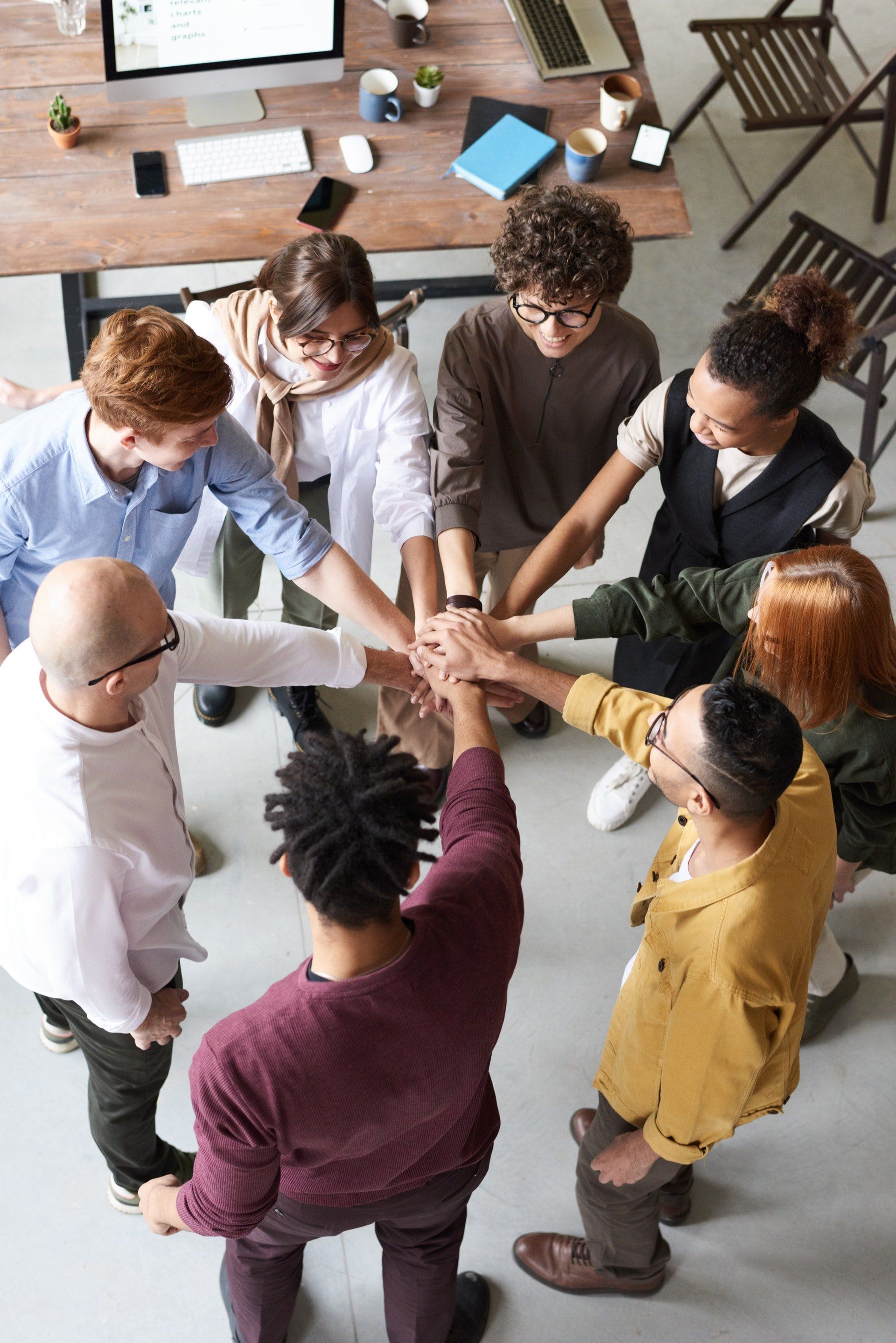 A group of people are putting their hands together in a circle.