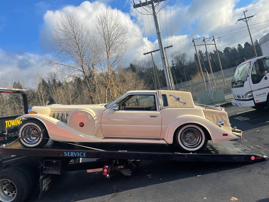 A white car is sitting on top of a tow truck.