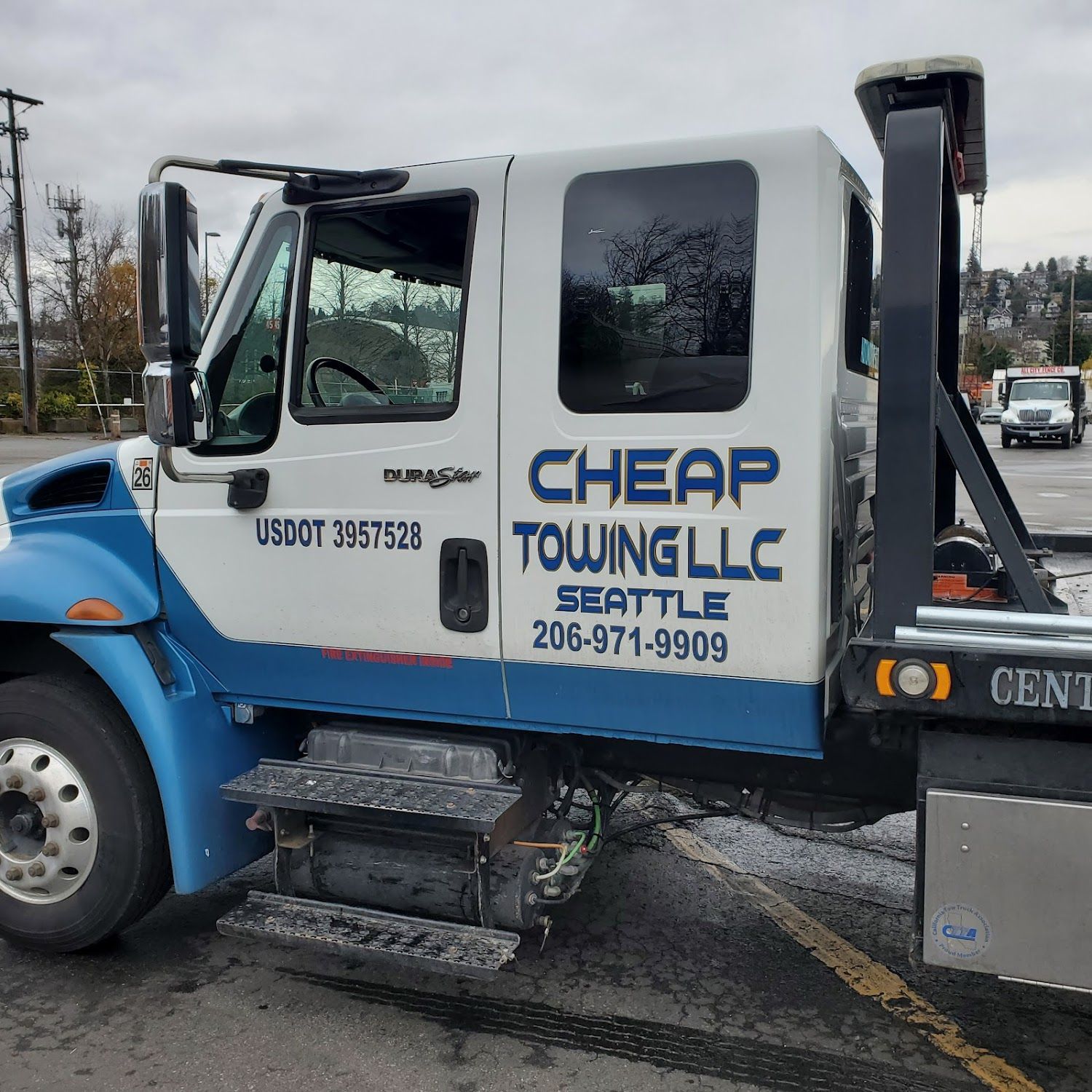 A blue and white towing truck is parked in a parking lot.
