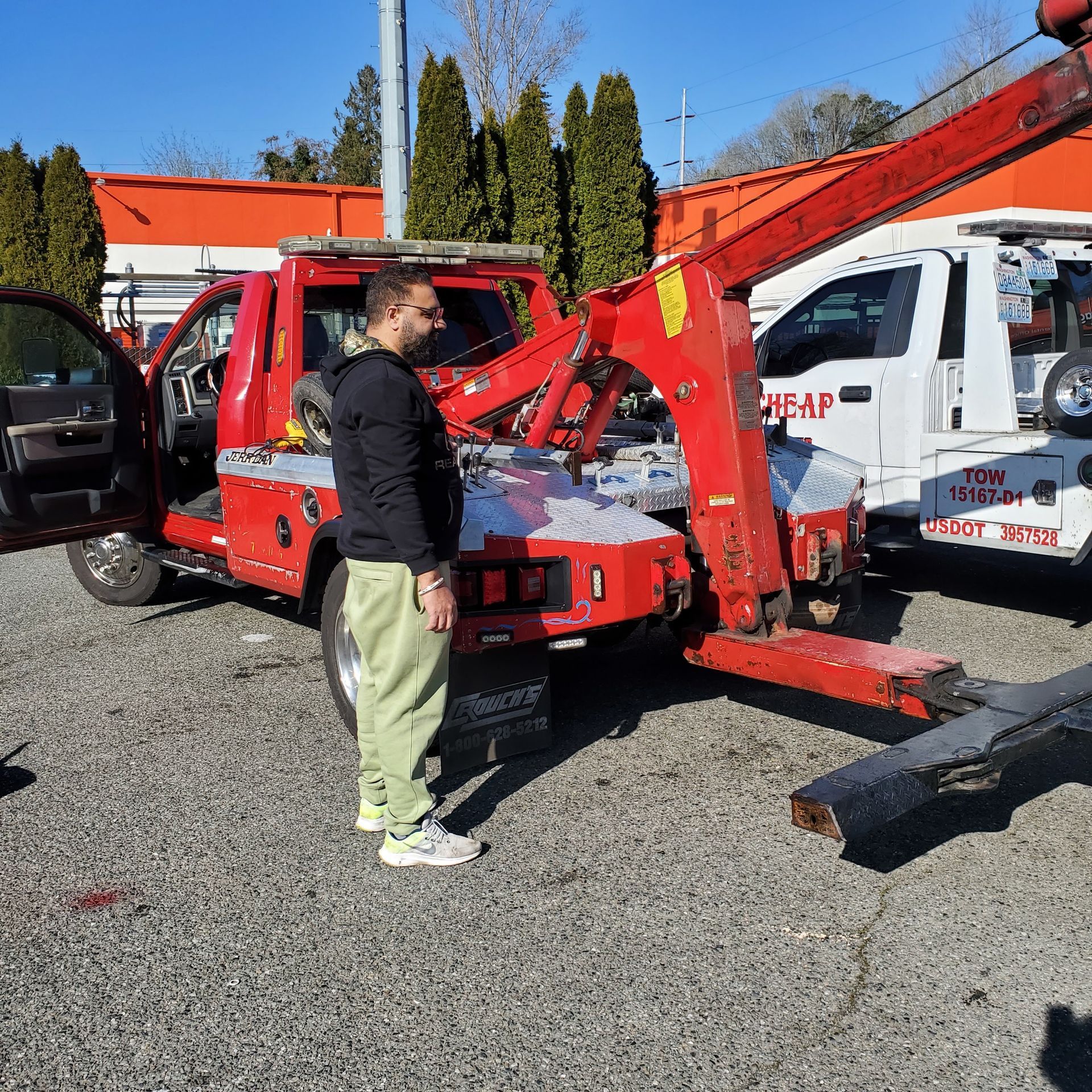 A man is standing in front of a tow truck that says cheap on it