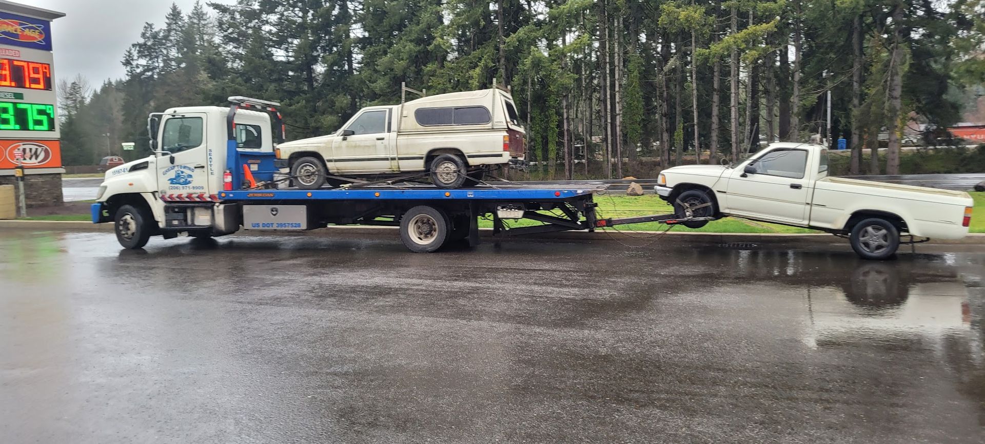 Two trucks are being towed by a tow truck in a parking lot.