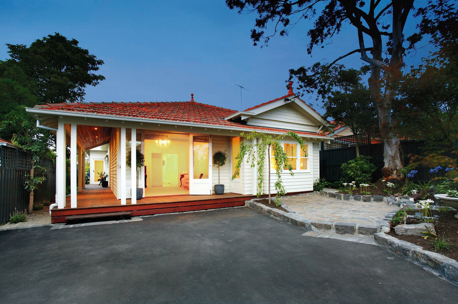 A White House With a Red Roof is Surrounded by Trees — KM Custom Homes In Mount Eliza, VIC
