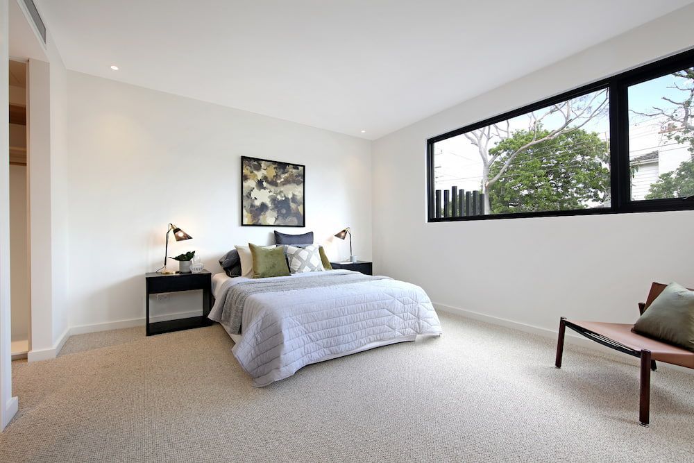 A Bedroom With A Large Bed And A Glass Door Between The Bedroom — KM Custom Homes In Mornington Peninsula, VIC