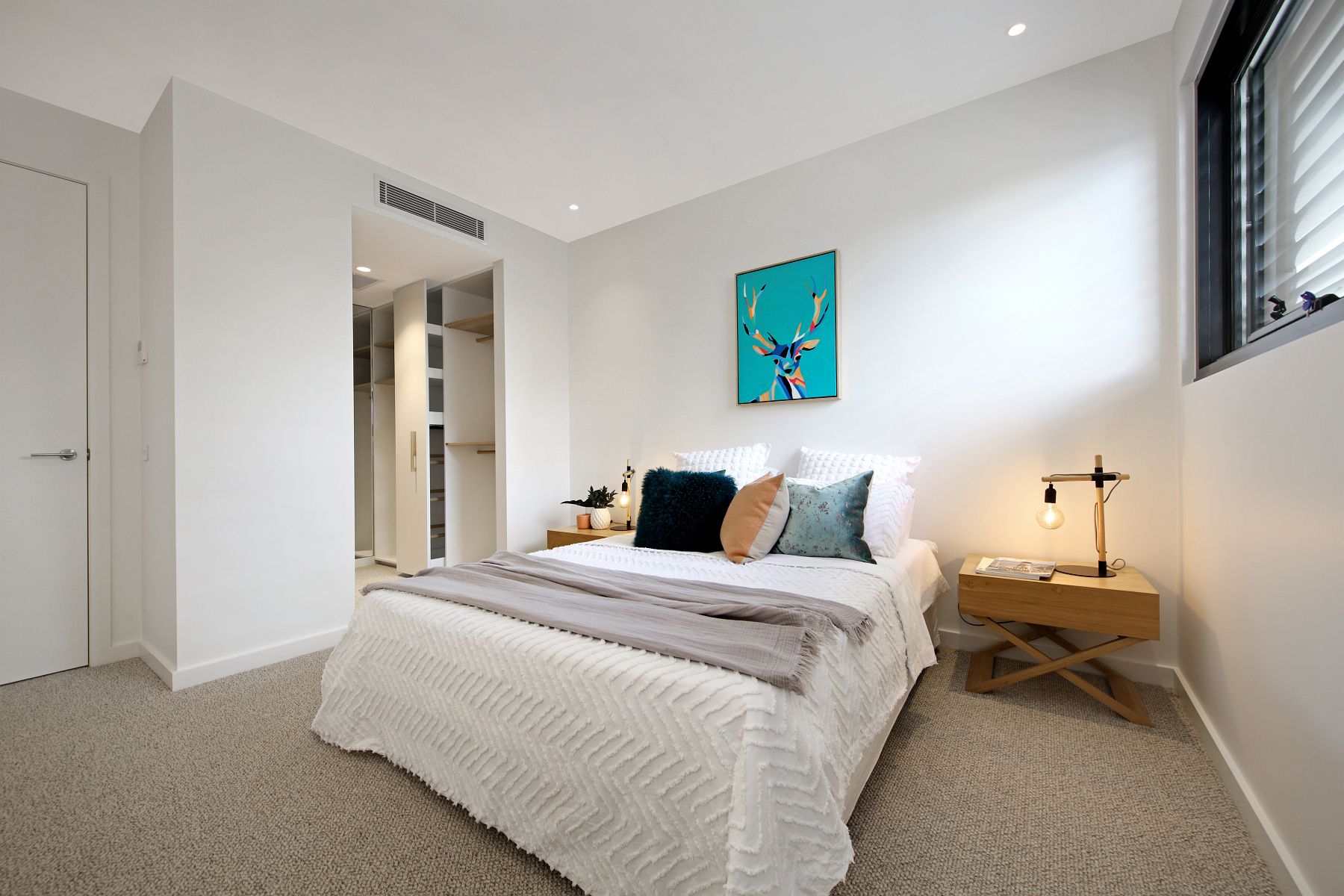 A Bedroom With A Bed, Nightstand, Lamp And Painting On The Wall — KM Custom Homes In Mount Martha, VIC
