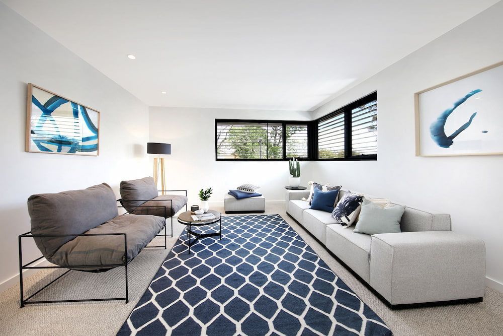 A Living Room With A Couch, Chairs, And A Rug — KM Custom Homes In Mount Martha, VIC