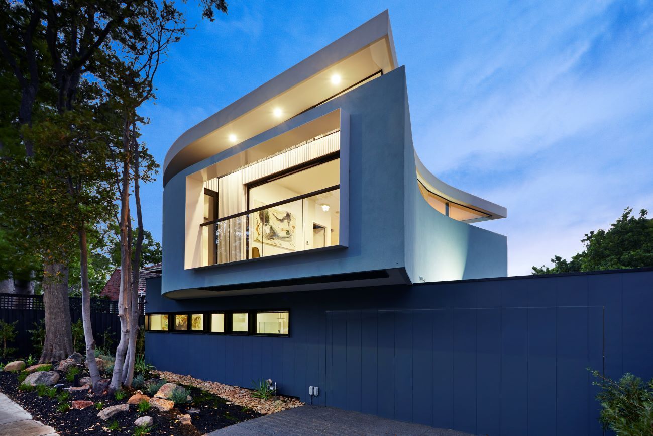 A Modern House With a Curved Roof is Surrounded by Trees — KM Custom Homes In Mount Eliza, VIC