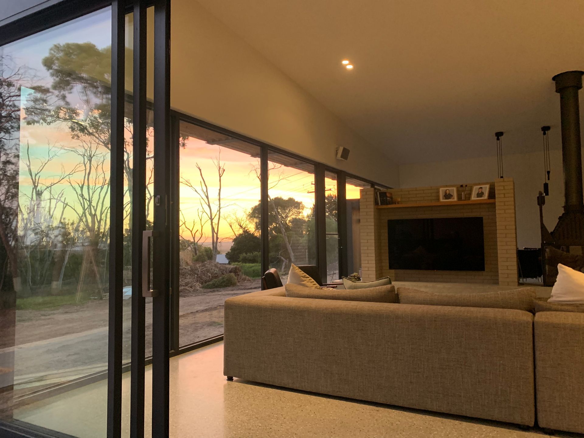 A Living Room With A Couch Television  Fireplace And Sliding Glass Doors — KM Custom Homes In Mornington, VIC