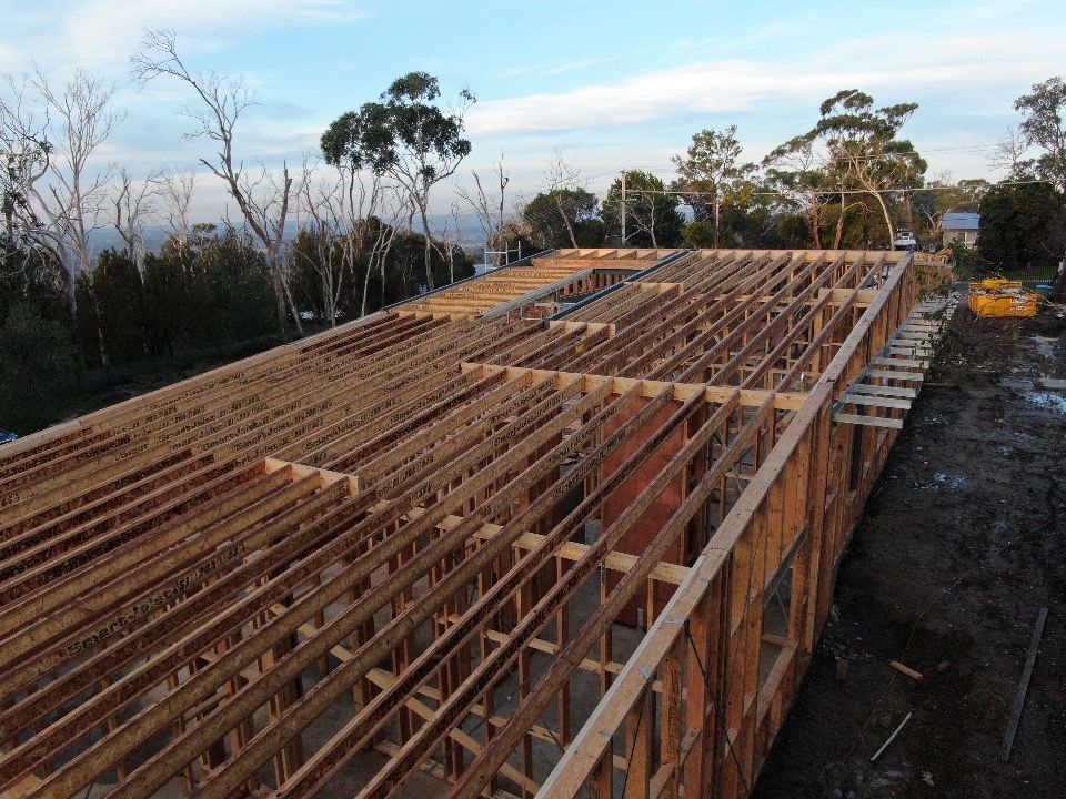 A Group Of People Are Standing In Front Of A House Under Construction — KM Custom Homes In Mount Eliza, VIC