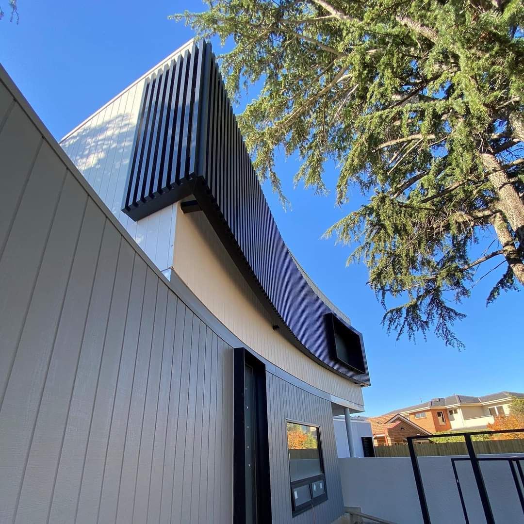 A Building With a Tree in the Foreground and a Blue Sky — KM Custom Homes In Mount Eliza, VIC