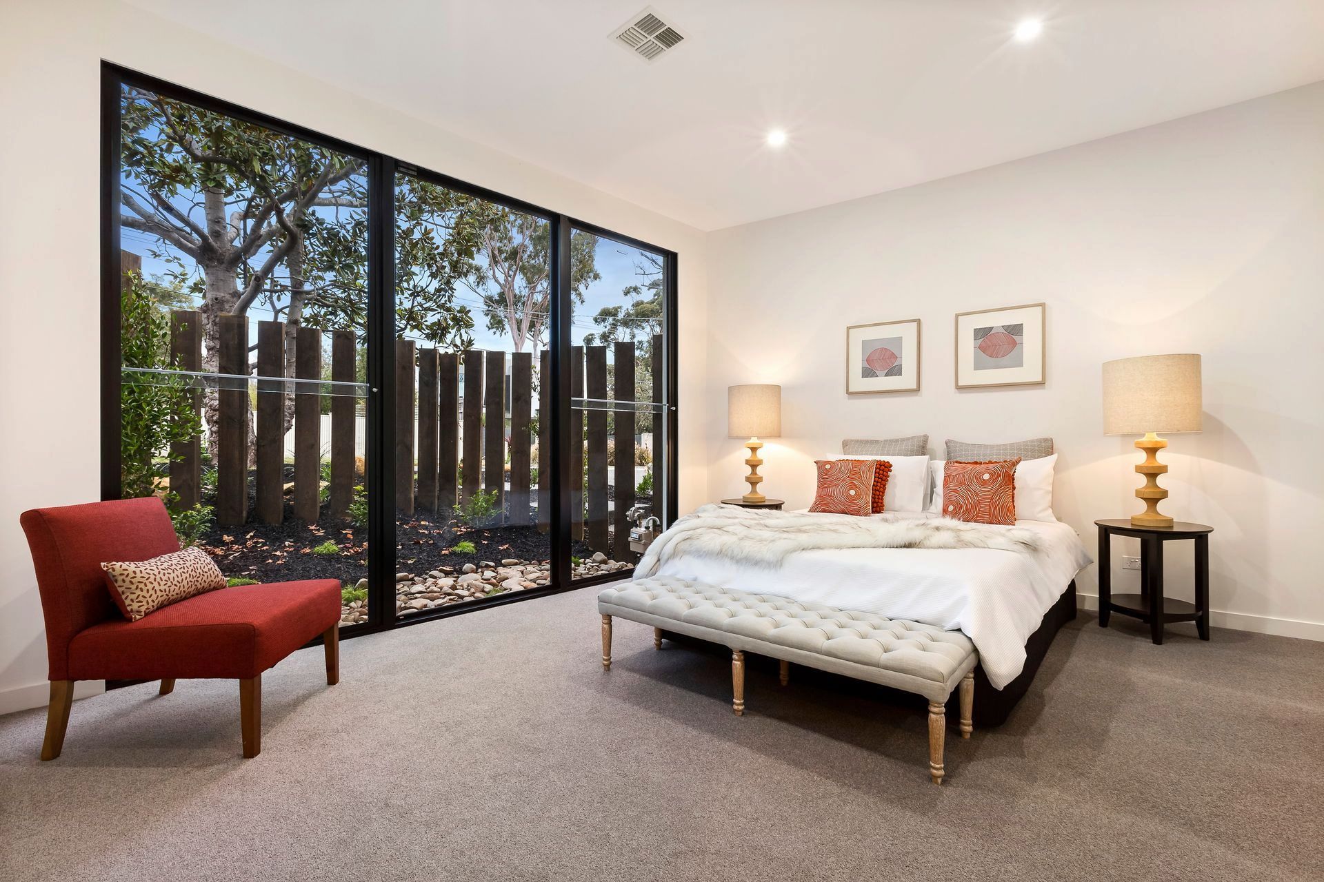 A Bedroom With A Large Bed And A Red Chair — KM Custom Homes In Mount Eliza, VIC