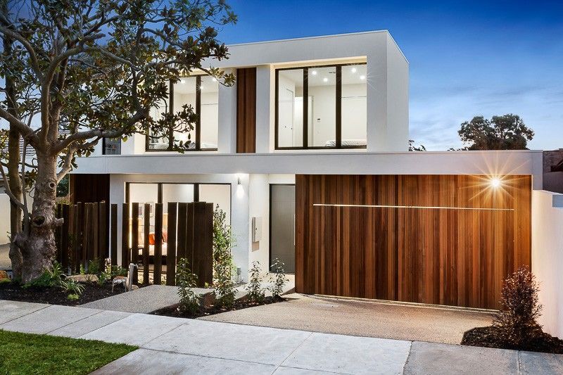 A Modern House With a Wooden Garage Door and a Tree in Front of It — KM Custom Homes In Mount Eliza, VIC