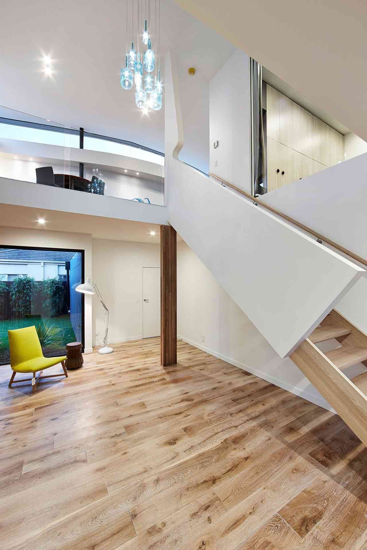 A Living Room With a Wooden Floor and Stairs Leading Up to the Second Floor — KM Custom Homes In Mount Eliza, VIC