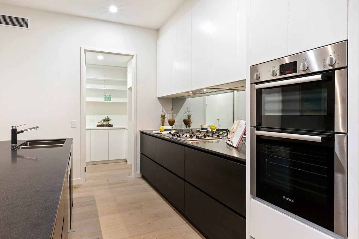 A Kitchen With Black Cabinets and a Stainless Steel Oven — KM Custom Homes In Mount Eliza, VIC