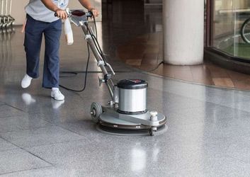 A person is using a machine to clean a tiled floor.