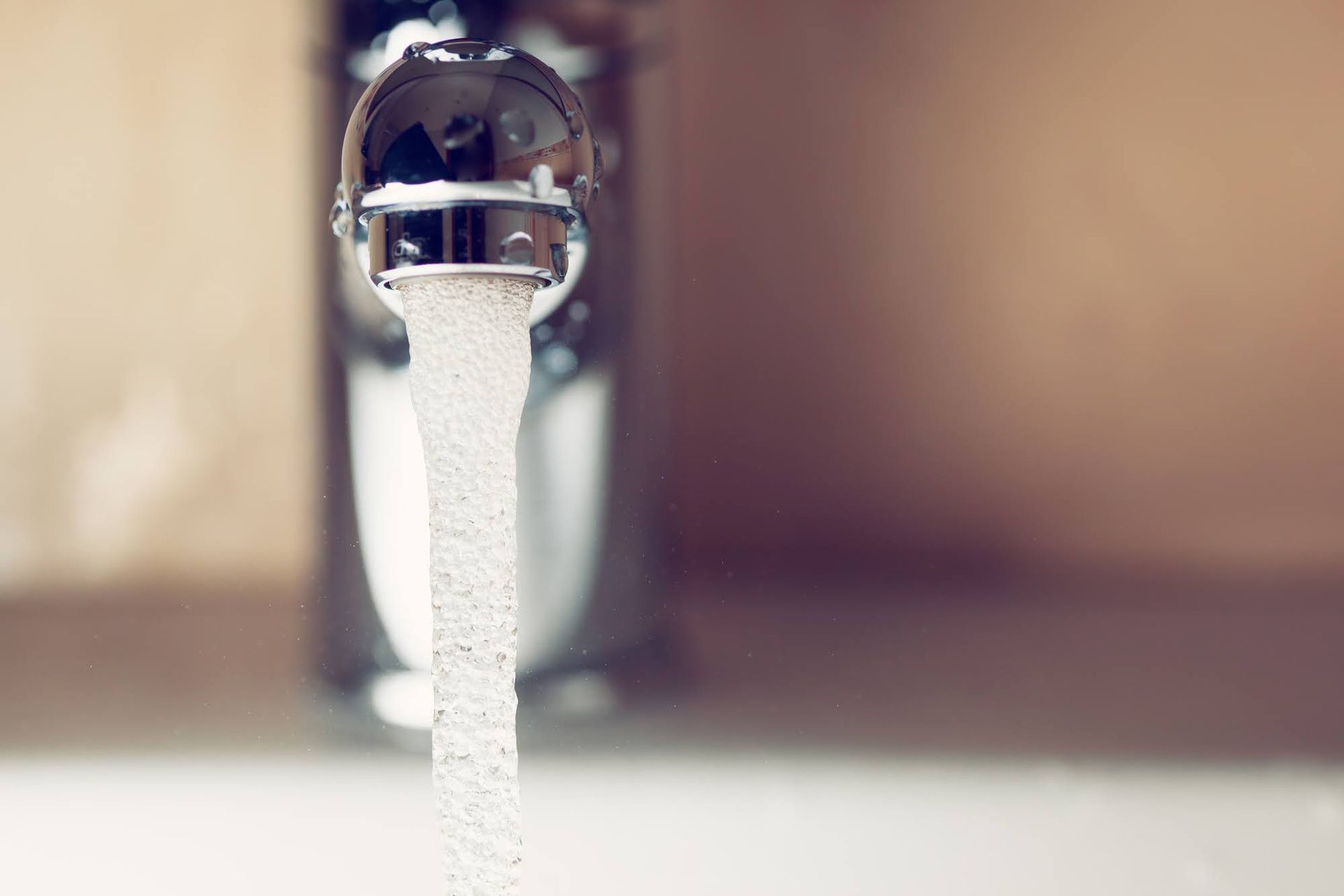 A close up of a water faucet with water running out of it.