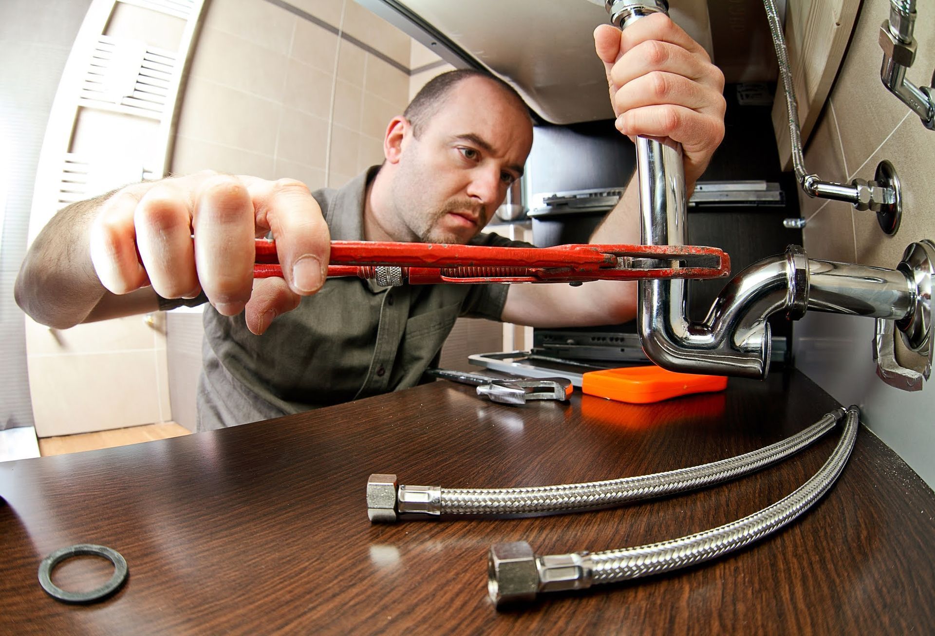 A man is fixing a pipe with a wrench.