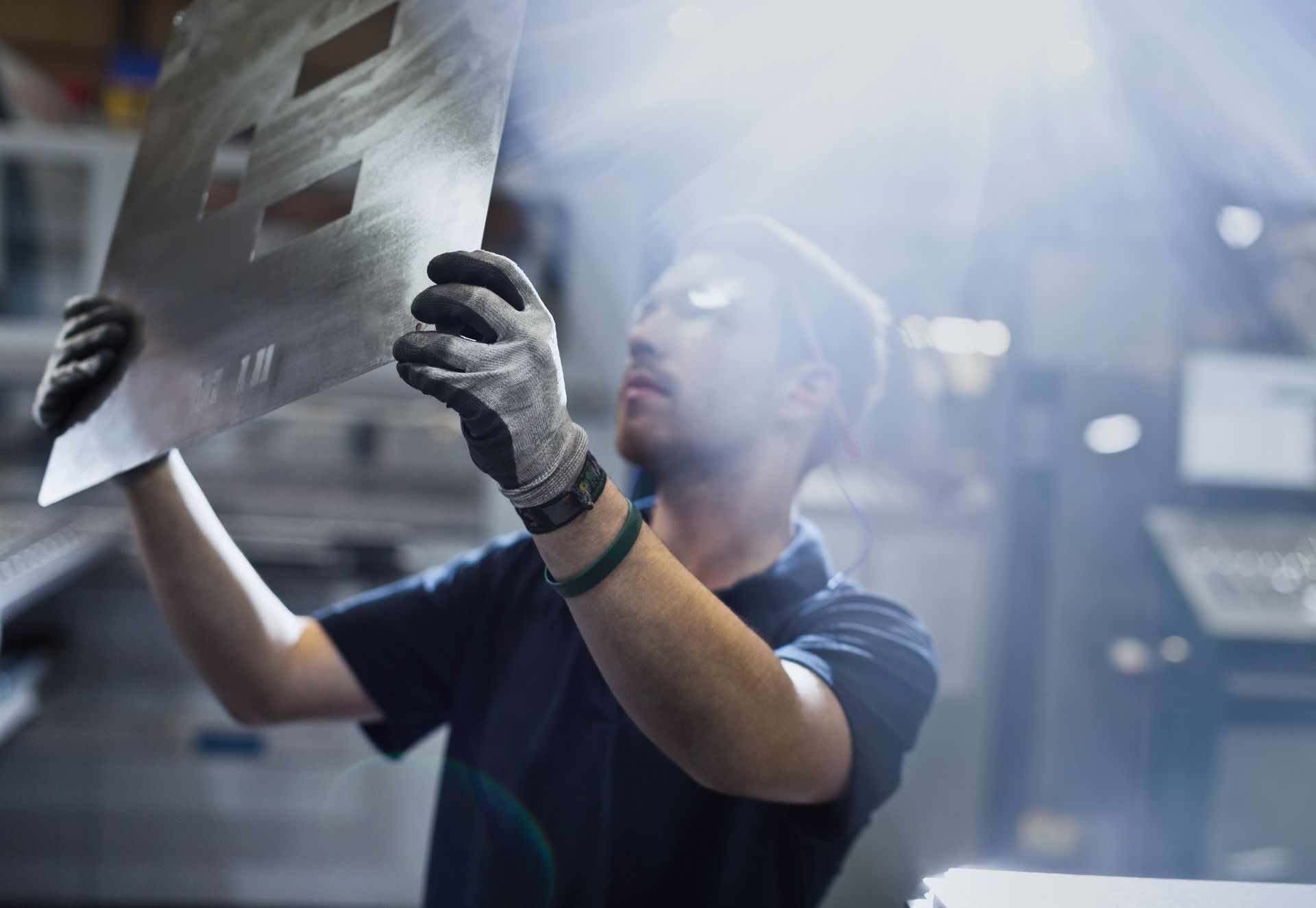 Un homme tient un morceau de métal dans ses mains dans une usine.