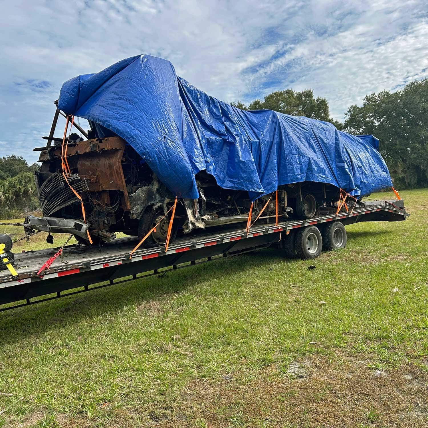 A white Keefer's Junk Removal truck is towing a black car down a street.