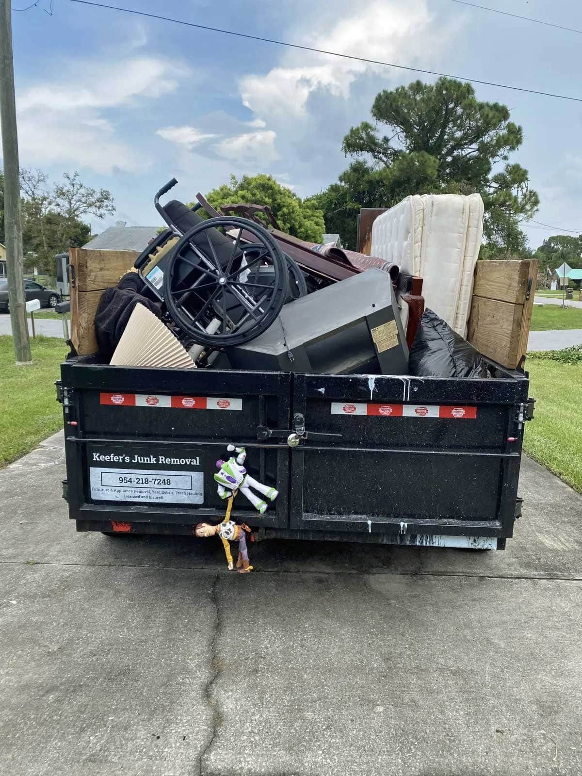 A dumpster filled with junk is parked on the side of the road.