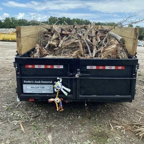 A trailer filled with wood is sitting on the ground.