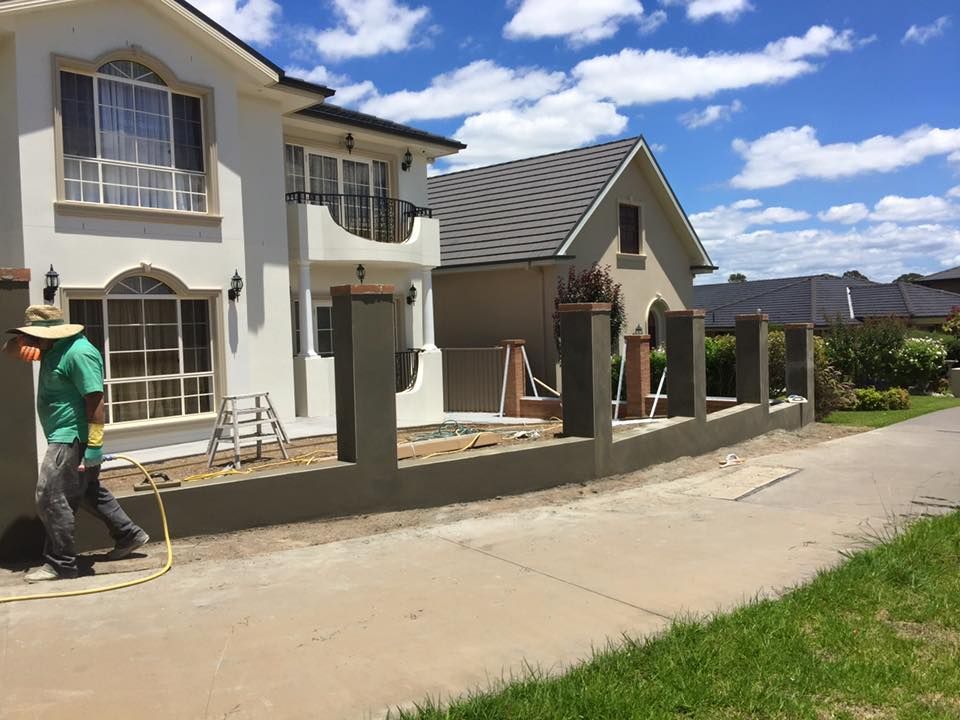 a man is spraying a fence in front of a house .