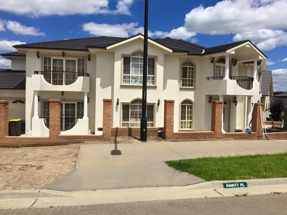 a large white house with a brick fence in front of it
