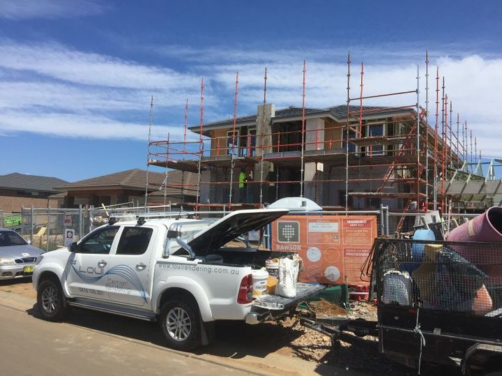 a white truck is parked in front of a house under construction .