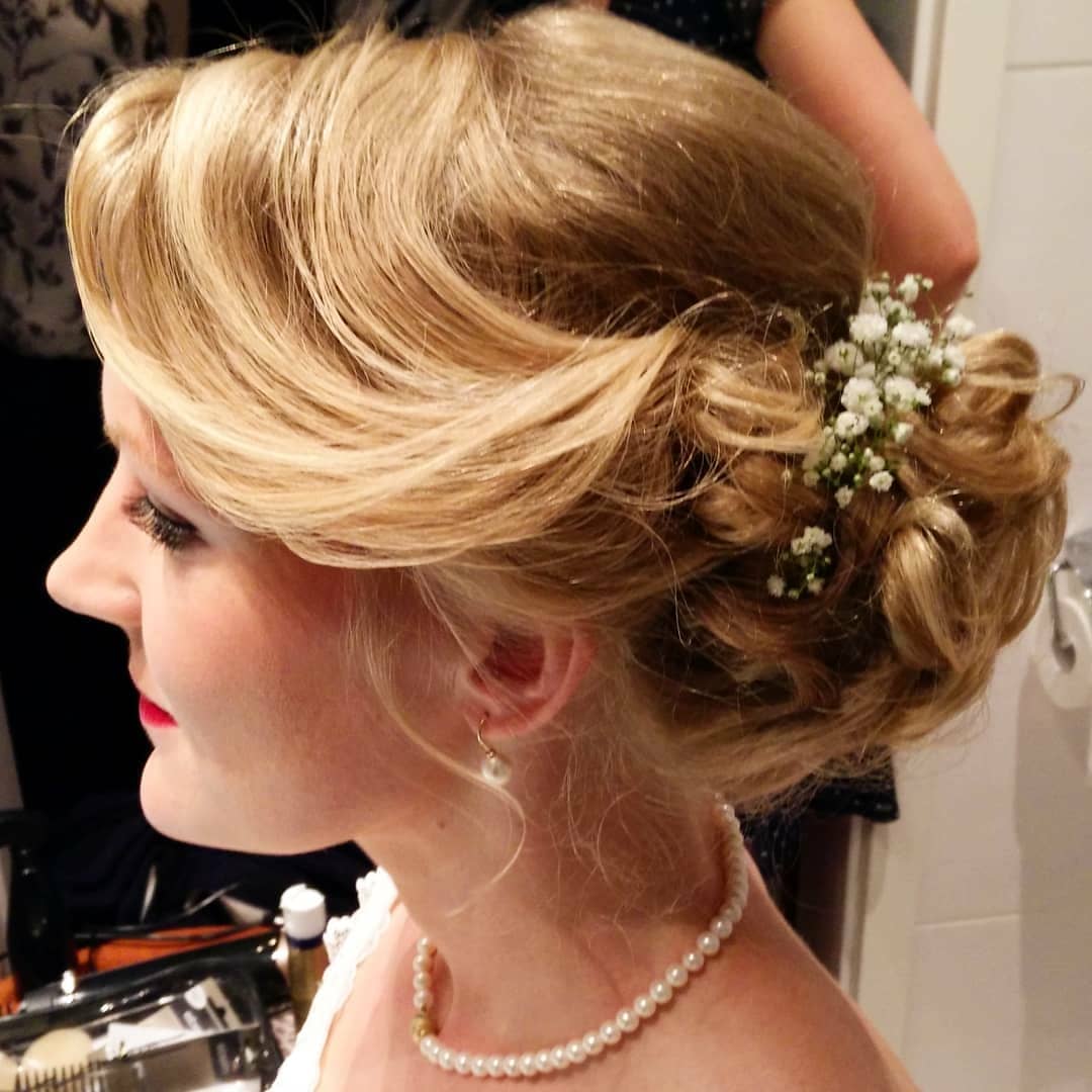 Die Frau trägt eine Perlenkette und hat Blumen im Haar