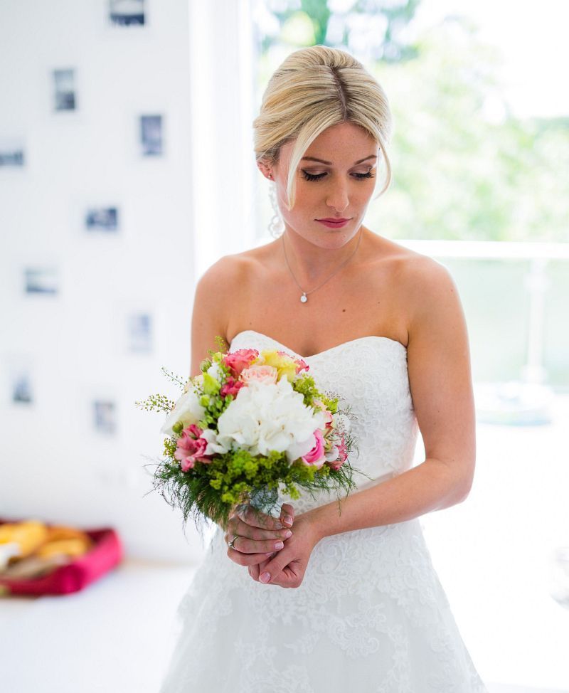 Eine Frau in einem Brautkleid hält einen Blumenstrauß