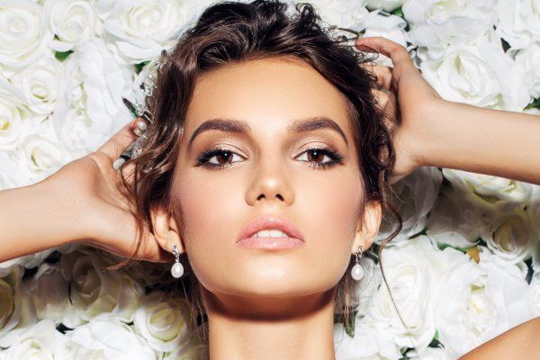 Eine Frau liegt auf einem Bett aus weißen Rosen.