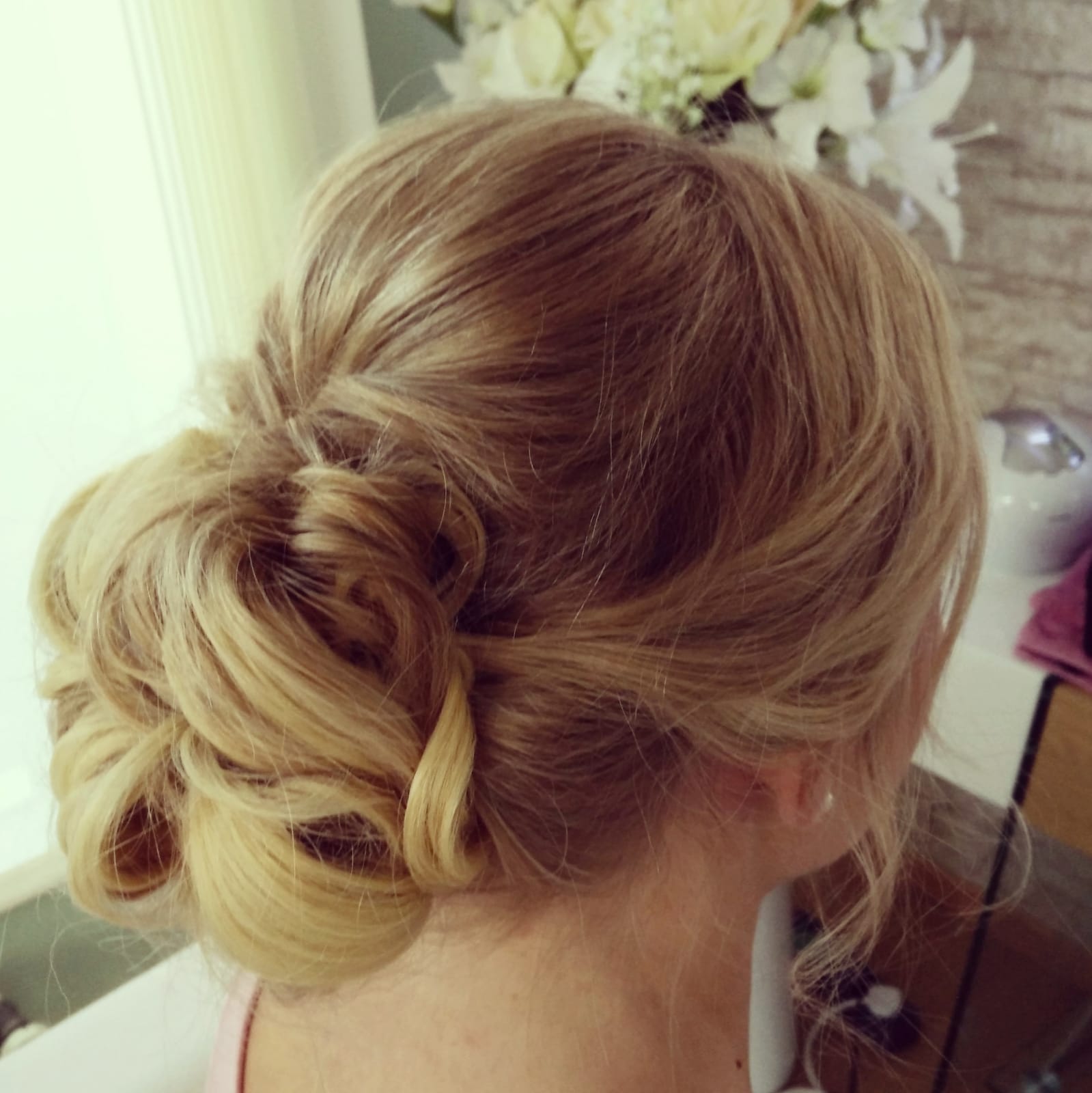 Eine Frau mit blondem Haar zu einem Dutt sitzt vor einem Fenster.