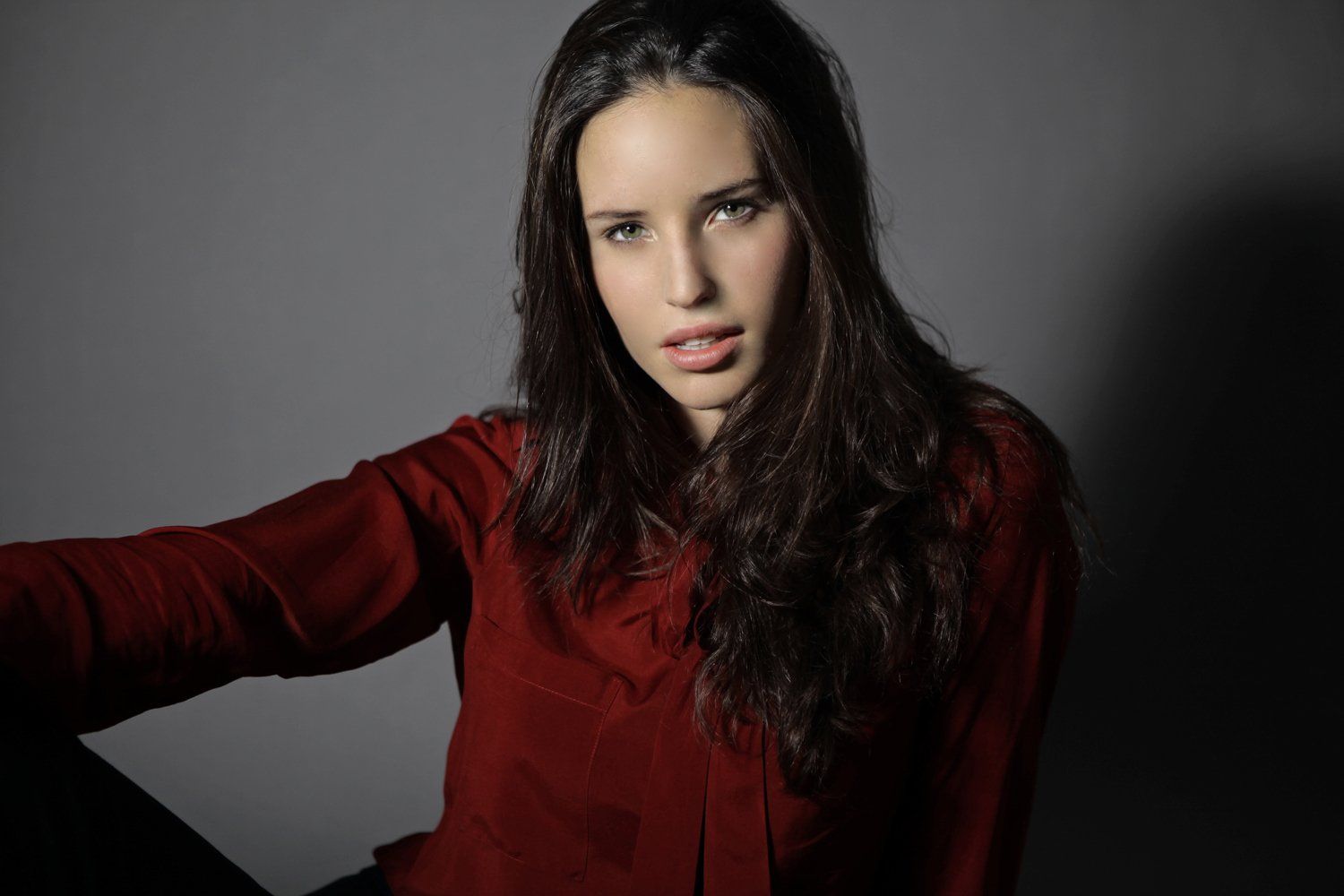 Eine Frau in einem roten Hemd sitzt da und schaut in die Kamera.