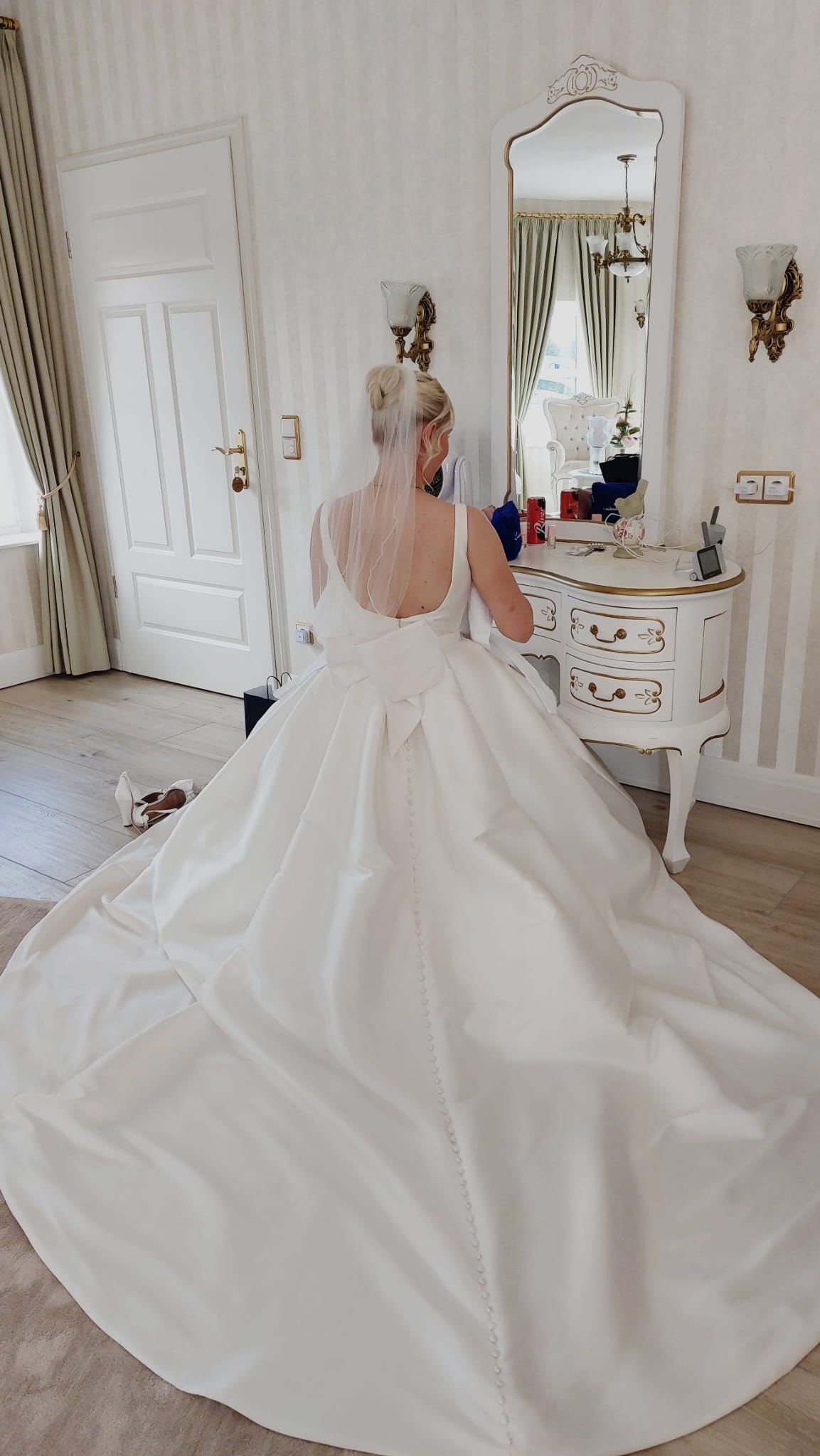 Eine Frau in einem Brautkleid steht in einem Zimmer vor einem Spiegel.