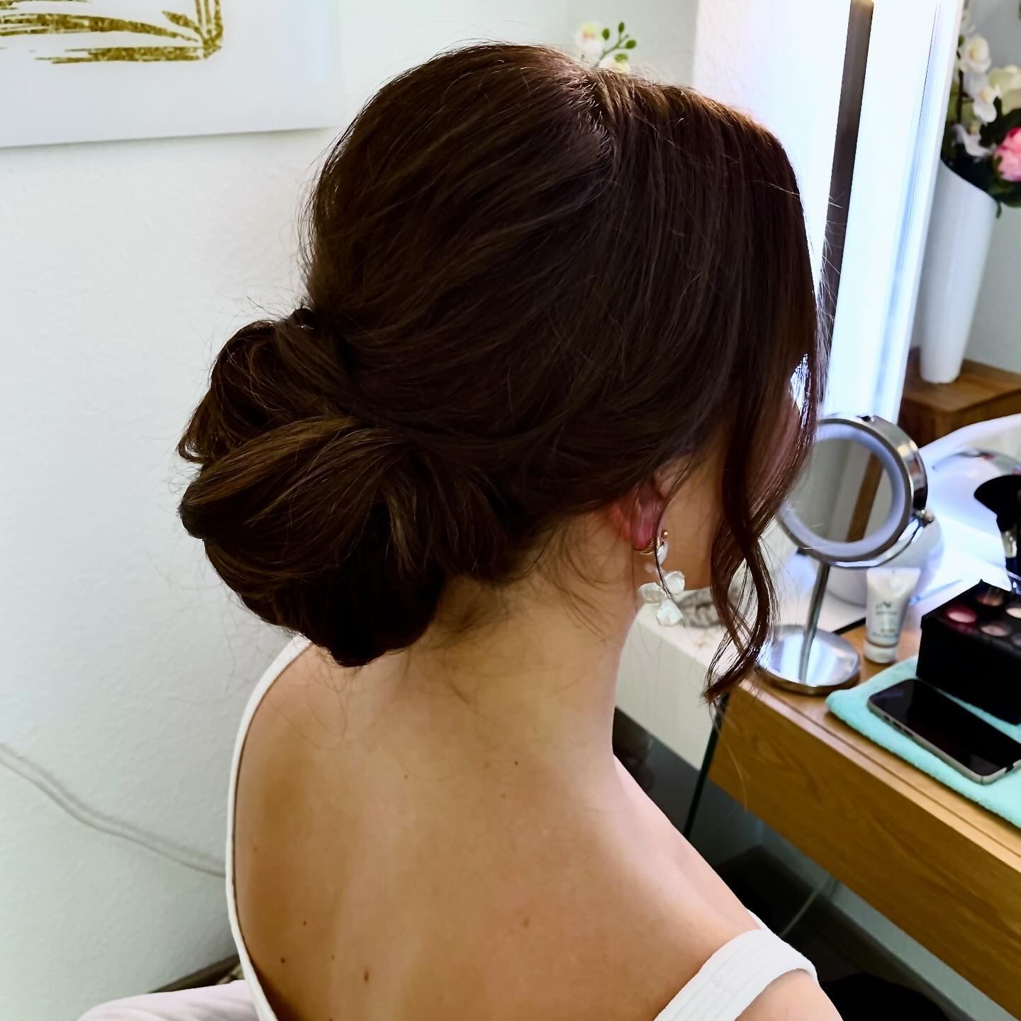 Eine Frau mit einem Dutt sitzt vor einem Spiegel.