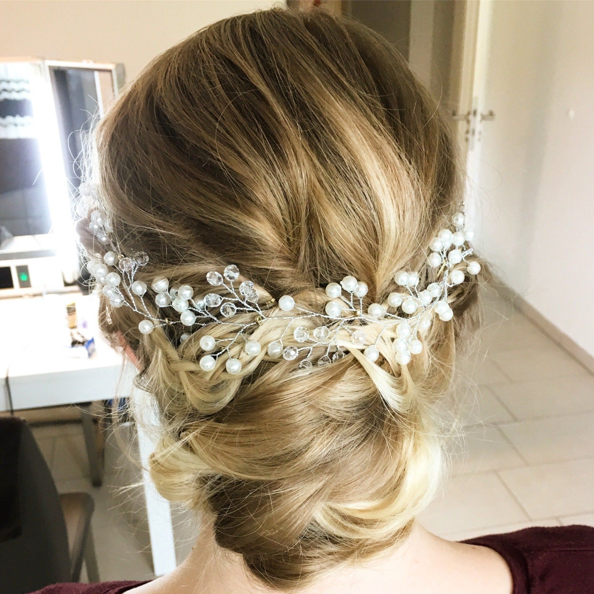 Eine Frau trägt einen Dutt mit Perlen im Haar.