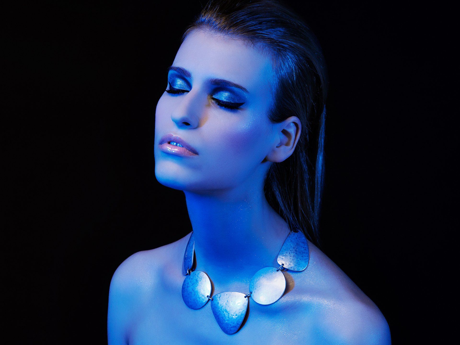 Eine Frau mit blauer Farbe im Gesicht trägt eine Halskette.