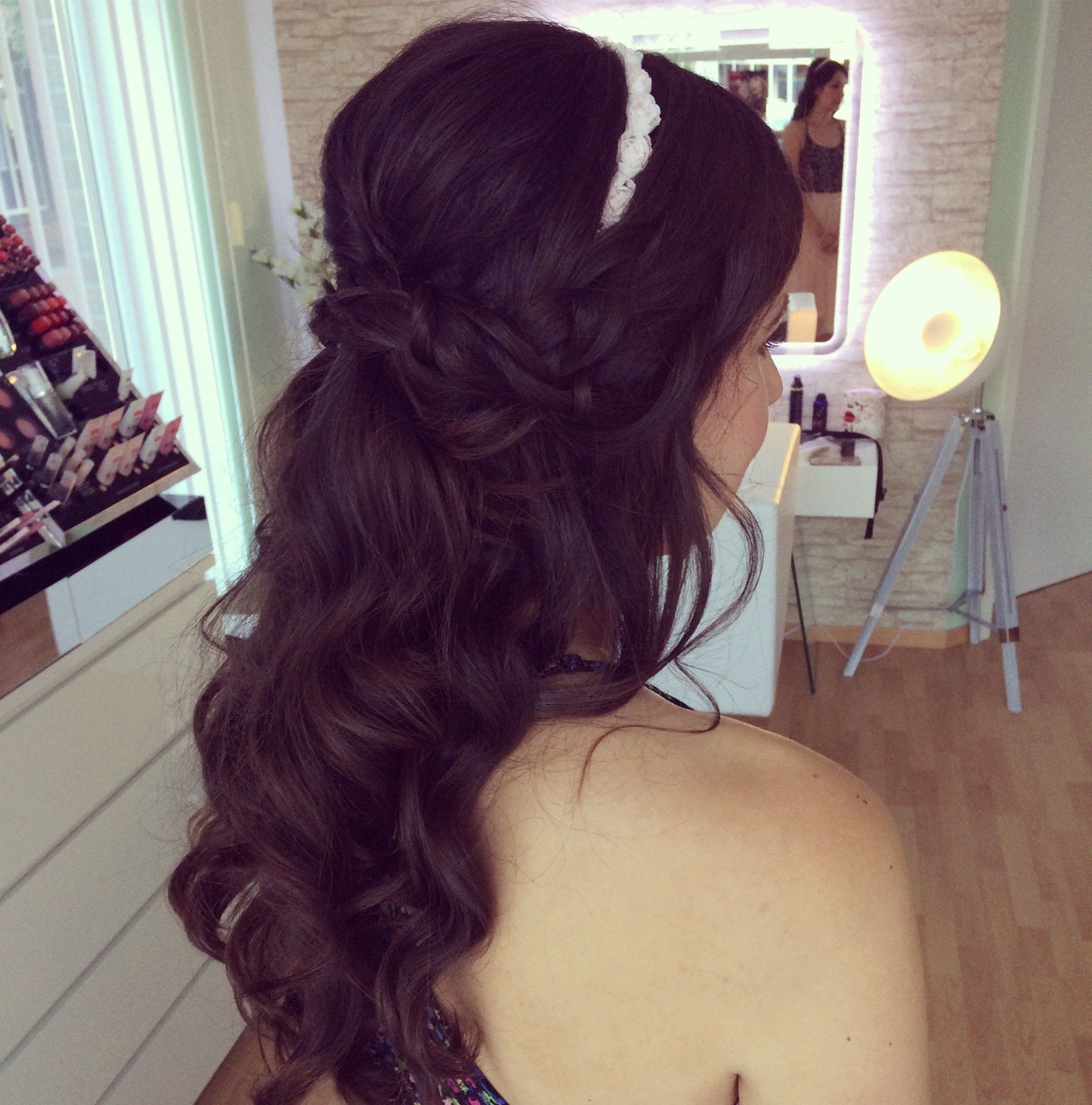 Eine Frau trägt eine halb hochgesteckte, halb herunterhängende Frisur vor einem Spiegel