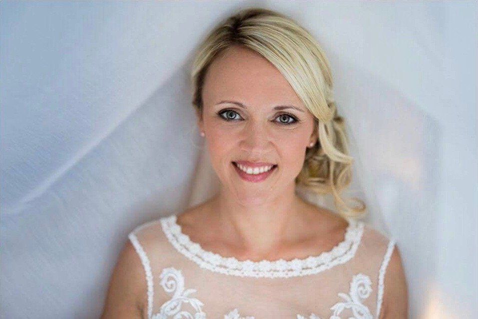 Eine Frau in einem Brautkleid und Schleier lächelt in die Kamera.