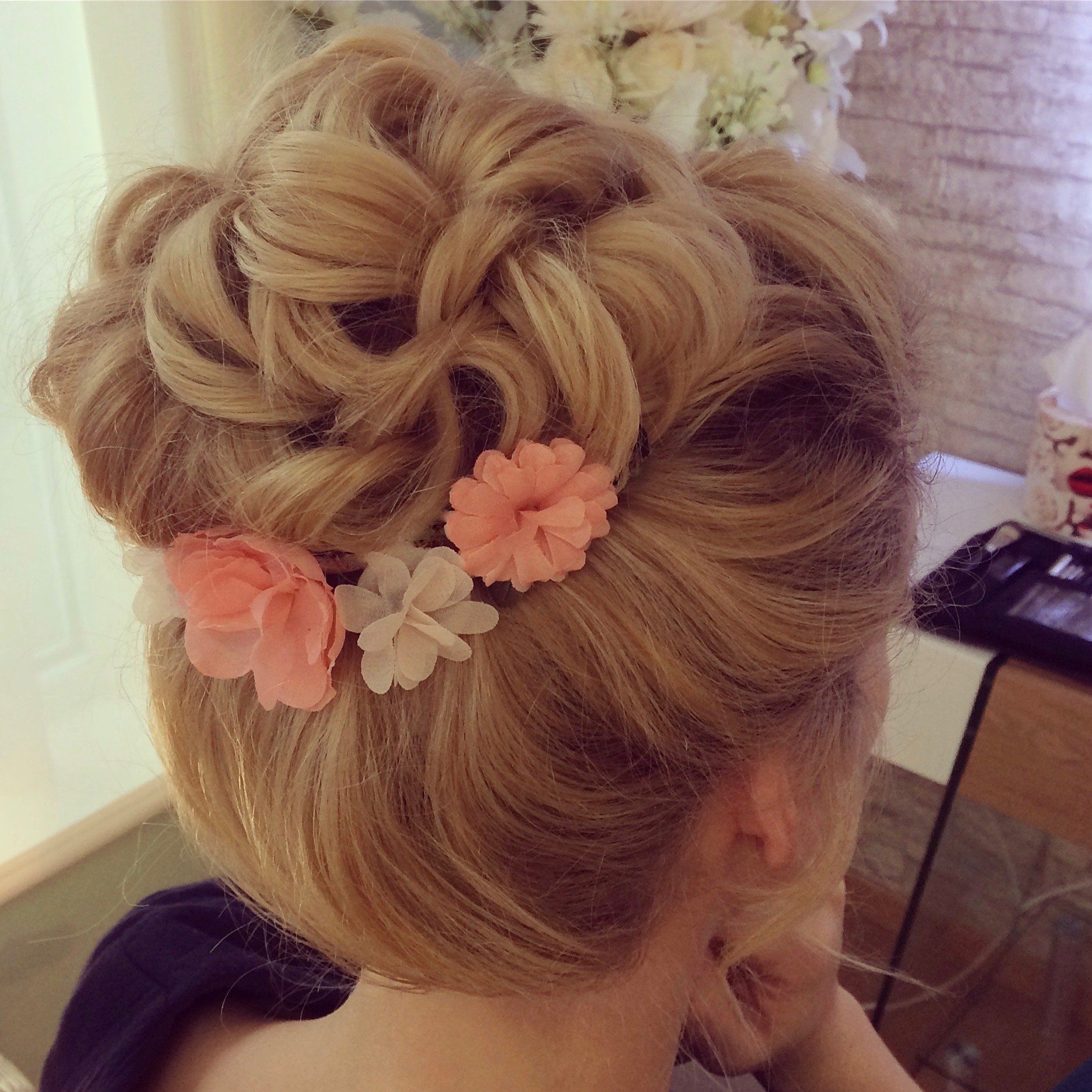 Das Haar einer Frau ist zu einem Dutt mit Blumen darin gebunden