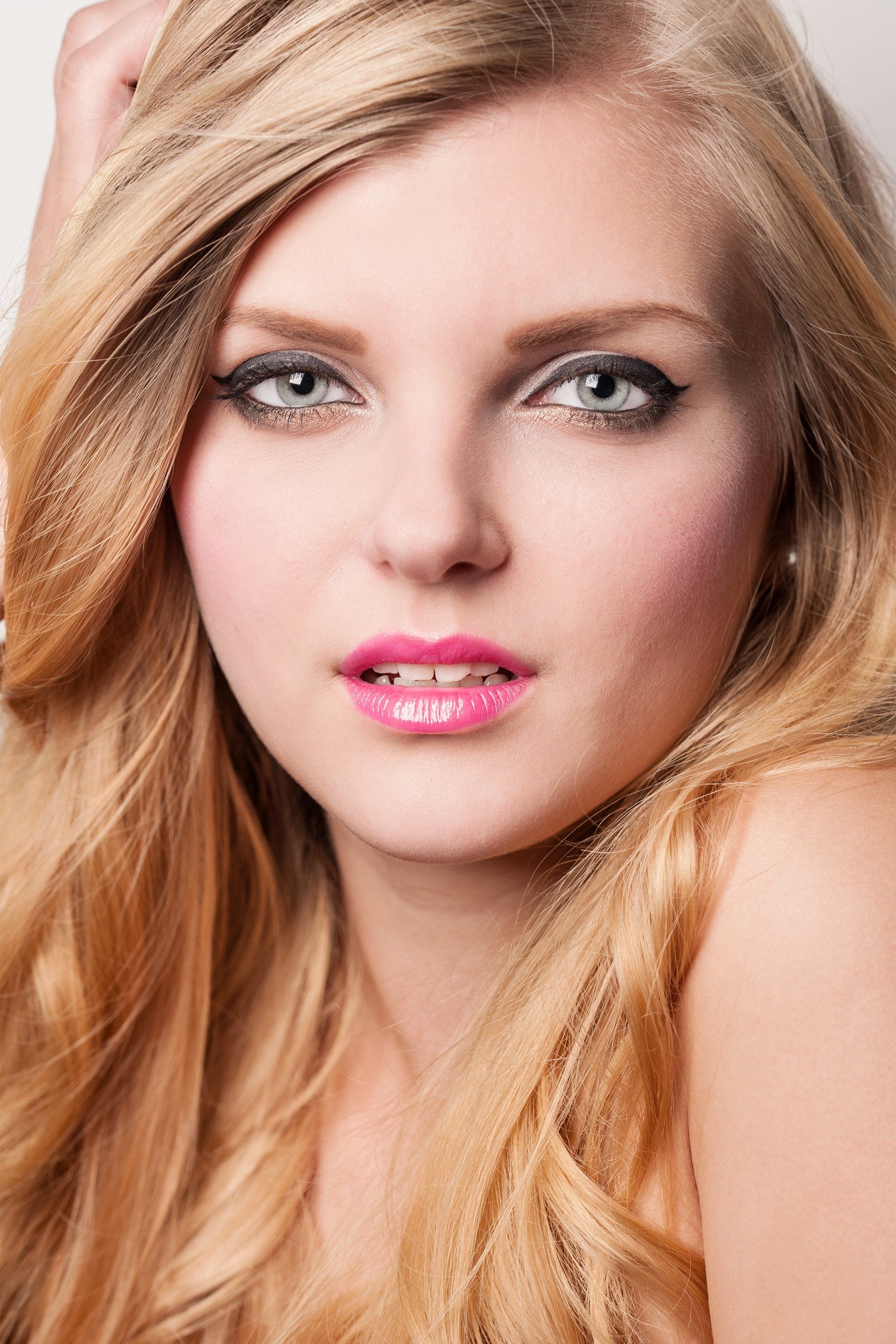 Eine Nahaufnahme des Gesichts einer Frau mit langen blonden Haaren und rosa Lippen.