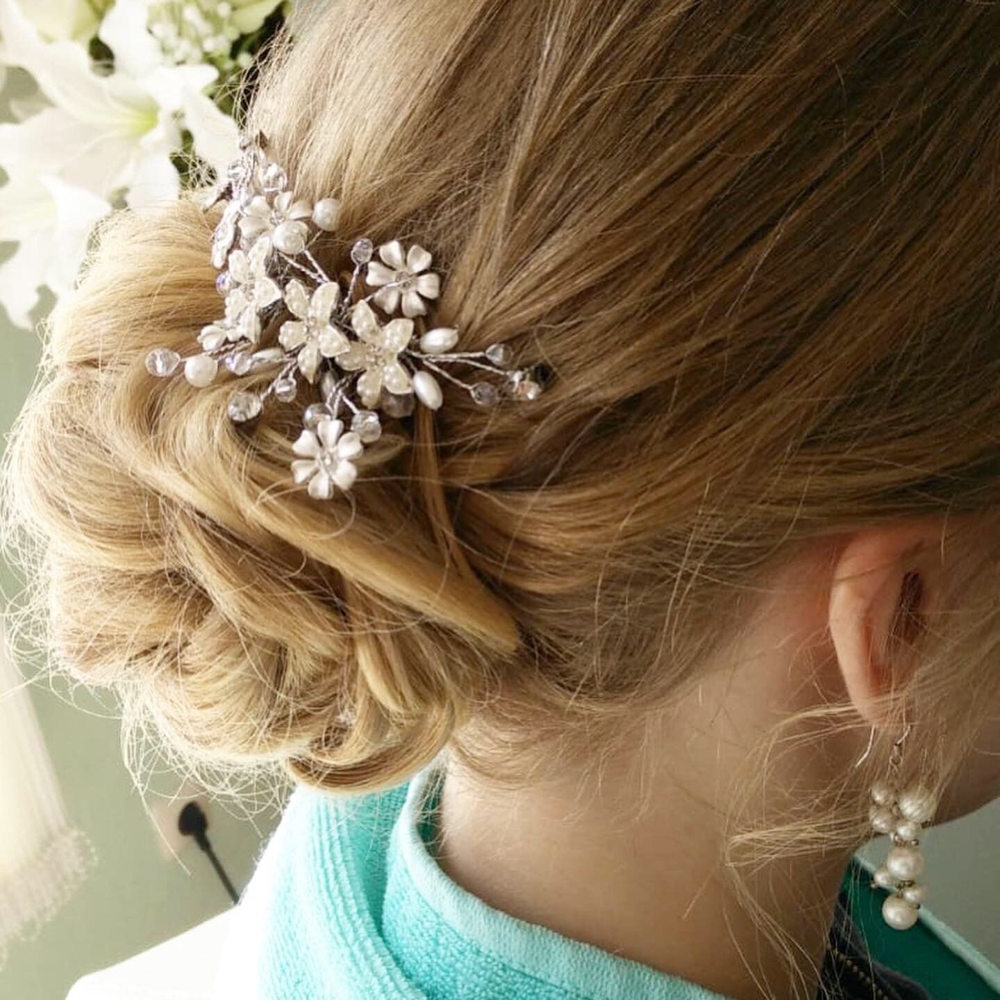 Eine Frau trägt einen Dutt mit Blumen und Perlen im Haar