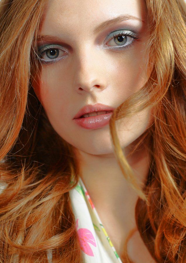 Eine Nahaufnahme des Gesichts einer Frau mit roten Haaren und blauen Augen.